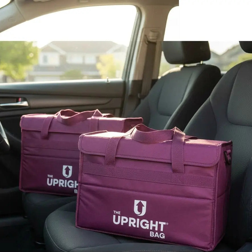 Two purple 'The Upright insulated food delivery Bag' on a car seat with blurred outdoor background