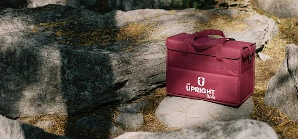 Red insulated bag labeled 'Upright Bag' on a rocky surface