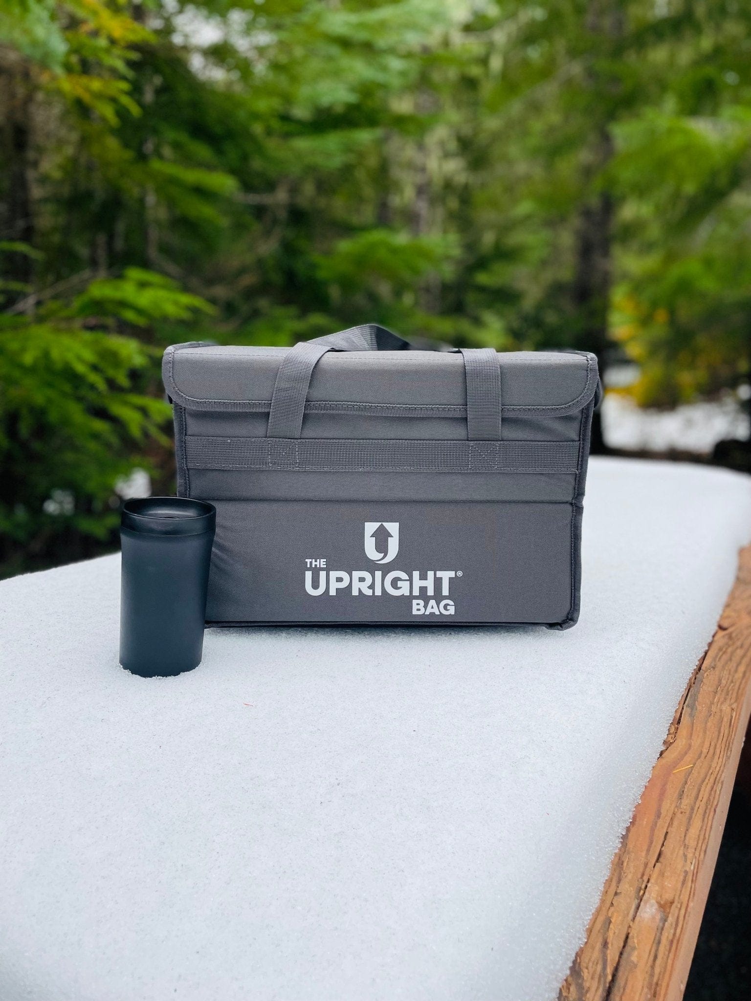 Gray 'The Upright thermal Bag' on a white surface with a forest background